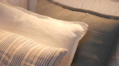 Yastıklar, yumuşak ışığın içinden geçtiği bir yatağa dizilir..