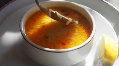 Sıcak çorba bir dilim limonla servis edilir..