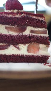 Biri kırmızı pastayı katmanlar ve meyvelerle keser..