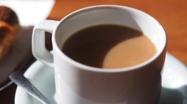 Kahvesini yudumlayan ve kafeteryada hamur işi yiyen biri..