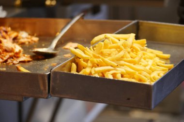 Yemek tezgahında servis edilecek taze patates kızartması var. Müşteriler emirlerini bekliyor..