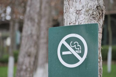 Park ortamındaki bir ağaçta sigara içme yasağı olduğu yazıyor..