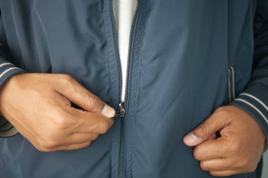 Biri mavi bir ceketin fermuarını iki eliyle kapatır, açık hava aktivitesine hazırdır..