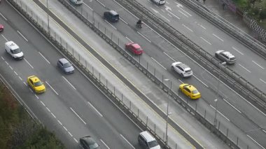 Gündüz vakti şehirde arabalar yoğun bir yol boyunca hareket eder..