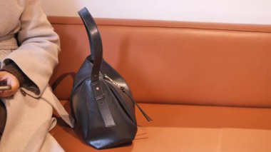 Akıllı telefonunu şık bir deri çantaya koyan bir kadın..