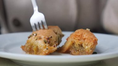 Çatal, fındıklı bir tabakta baklava topluyor..