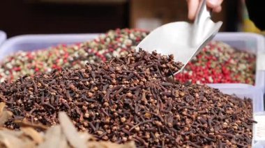 Bir insan bir marketteki büyük bir konteynırdan karanfil toplar..