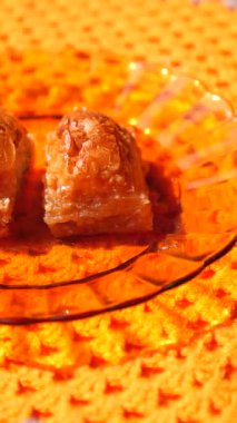 İnsanlar bir toplantıda parlak bir tabağa yerleştirilmiş tatlı baklavanın tadını çıkarırlar..