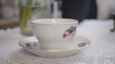 Bir insan rahat bir kafede porselen bardaktan çay yudumlar..