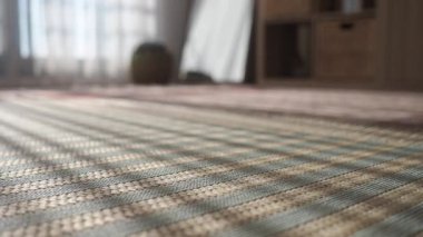 Odadaki örülmüş bir kilimin üzerinde parlayan bir pencere ışığı..