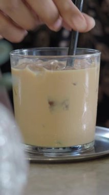 Bir insan geç saatte masada bir bardak buzu karıştırır..