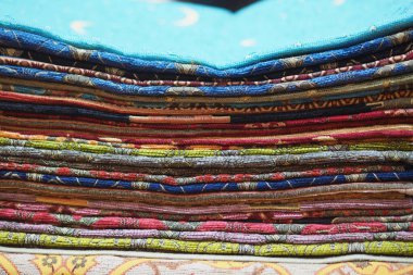 Farklı renkte kumaşlar bir markette masanın üzerine düzgünce istiflenir..