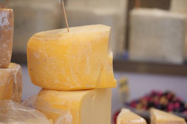 Sarı peynir parçaları elinde bıçakla markette bir masanın üzerinde oturuyor..