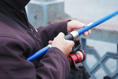 Rıhtımda balık tutmaya hazırlanırken biri oltayı tutuyor..