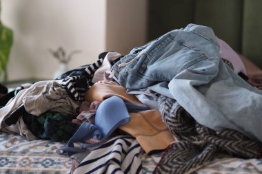 Gündüz vakti büyük bir giysi yığını bir yatağın üzerindedir..