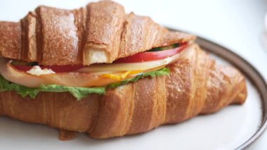 Kruvasan sandviçi peynir, marul ve domatesle doludur..