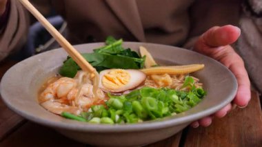 İnsan yemek çubuklarını erişte ve yeşillikli karides yemek için kullanır..