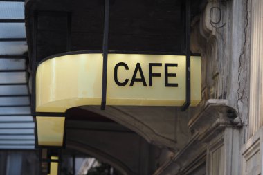 Gündüz vakti bir caddenin üzerinde bir kafe tabelası asılı..