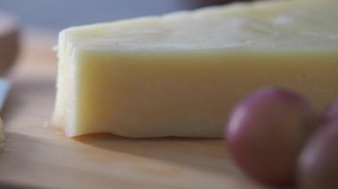 Mutfaktaki ahşap bir tahtanın üzerinde peynir ve üzümlerin yakın plan görüntüsü..