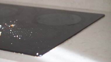 Bir insan yemek hazırlığından sonra kırıntıları ve lekeleri olan bir fırını temizler..