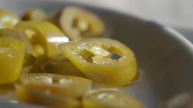 Dilimlenmiş jalapeno biberleri yemeye hazır beyaz bir tabakta otururlar..