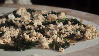 Bir el, hamur işi için yeşilliklere ve soğanlara peynir serper..