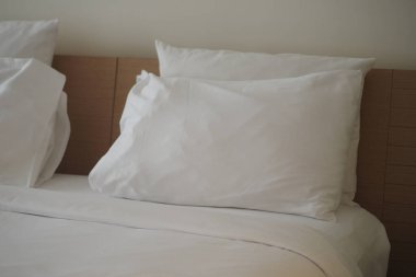 İki beyaz yastık, basit bir odada temiz çarşaflarla bir yatakta dinleniyor..