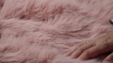 Bir el, yakın planda yumuşak pembe bir kumaşı keşfeder..