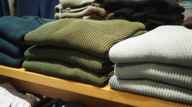 Müşteriler mağazanın içindeki bir rafta süveterleri karıştırıyor..