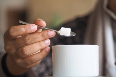 Kafedeki beyaz bardağa şeker küpü ekliyor. Sessiz bir an..