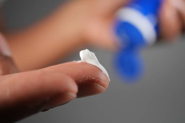 Bir insan cildini nemlendirmek için parmağına krem sürer..