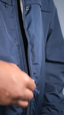 Bir insan serin havada evin içindeyken donanma ceketinin fermuarını çeker..