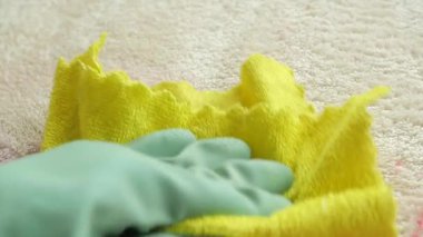 Bir insan kumaş kullanarak halıdan pembe bir leke çıkarır..