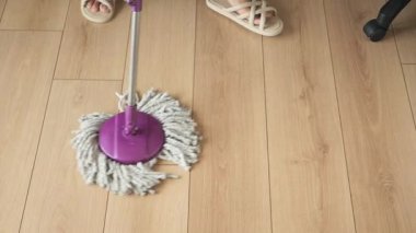 Birisi odasındaki ahşap zemini temizlemek için paspas kullanıyor..