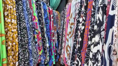 Bir giyim mağazası ortamında farklı kumaşlar gösteriliyor.