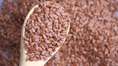 Keten tohumları tahtadan bir kaşıkta sergileniyor ve yüzeyde daha fazlası var..