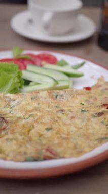 Bir insan lokantada taze sebzeli omlet yer..