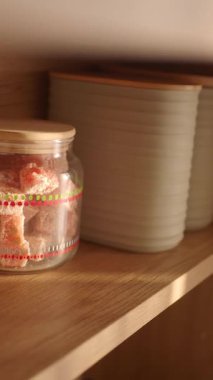 Cam bir kavanozda raftaki bazı kutuların yanında şeker var..