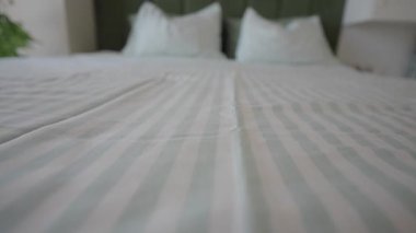 Kamera iki yastıkla yataktaki çizgili yorgana odaklanıyor..