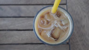 Bir insan dışarıda masada otururken buzlu kahve içer..