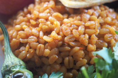 bulgur pilavı beyaz tabakta sebzelerle servis edilir..