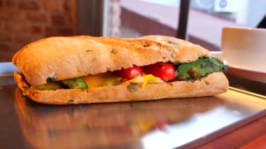 Bir kafede rahat bir yerde sebzelerle dolu bir sandviçin tadını çıkarıyorum..