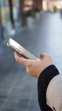 Bir insan şehir caddesinde yürürken akıllı telefon tutar..