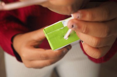 Bir insan içmek için yeşil bir kutuya pipet yerleştirir..