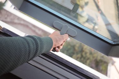 Bir el pencere mandalını tutuyor, gündüz açmaya hazırlanıyor..