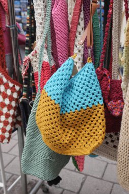 Kalabalık bir pazarda farklı çantalar sergileniyor..