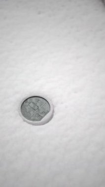 Bir madeni para kısmen kalın bir kar tabakasıyla kaplıdır..