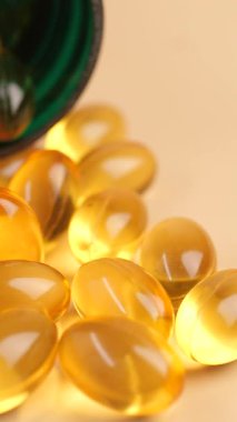 Yağ kapsülleri yeşil bir şişeden hafif bir yüzeye düşer..