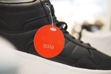 Siyah ayakkabılar kırmızı etiketli bir mağazada sergileniyor..