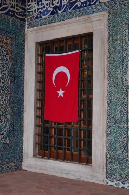 Renkli fayanslarla çevrili bir pencerede Türk bayrağı görülüyor.